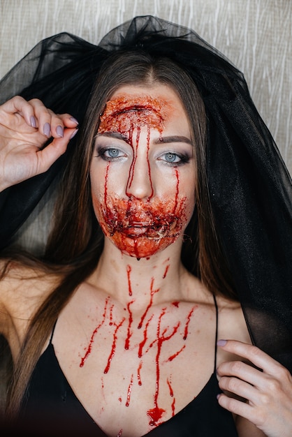 Gruselige blutige Make-up-Mädchen an Halloween. Künstliches Make-up und der Anlass.