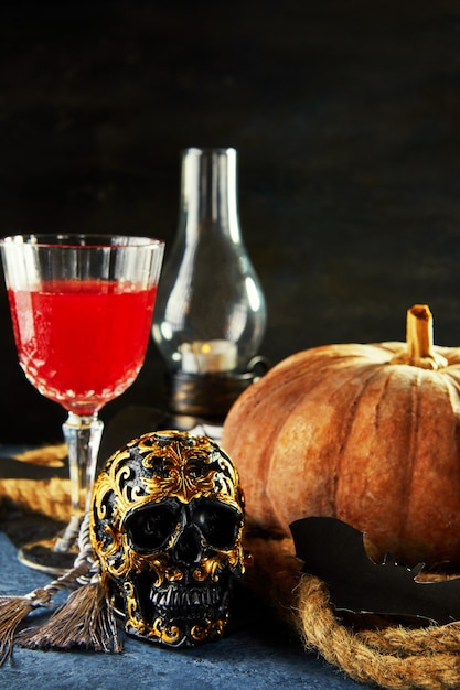 Gruseliger Halloween-Schädel mit Kürbis und Wein in einer gruseligen Nacht.