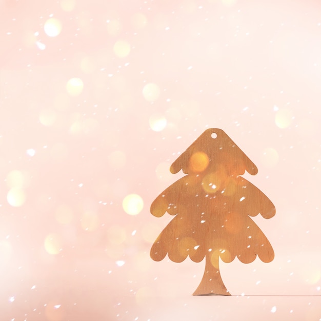 Grußkarte in minimalem Stil. Hölzerner Weihnachtsbaum auf rosa Hintergrund mit Kopienraum