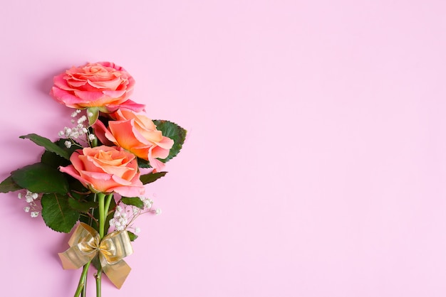 Grußkarte vom natürlichen Blumenstrauß der frisch gepflückten Rosenblumen auf einem pastellrosa Hintergrund.