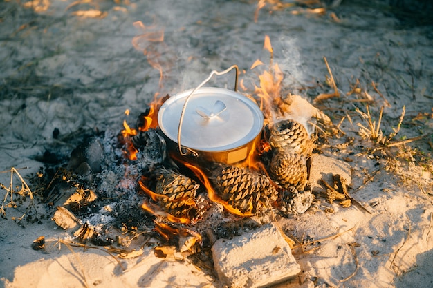 Água a ferver em panela de metal ao ar livre. Preparação de chá na natureza selvagem em viagem de acampamento. Equipamento turístico.