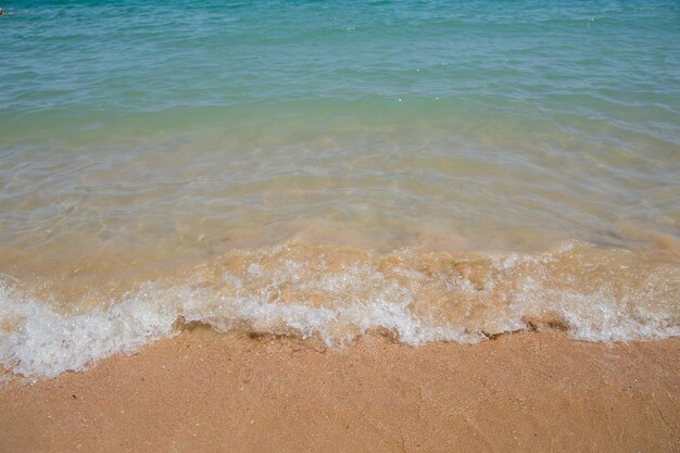 Água azul clara na praia com areia