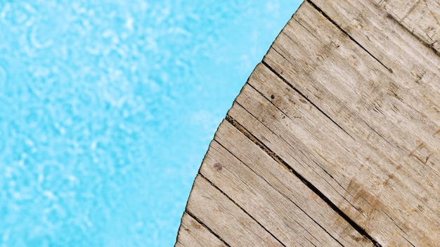 Água azul na piscina com reflexos de luz e fundo lateral da piscina de madeira