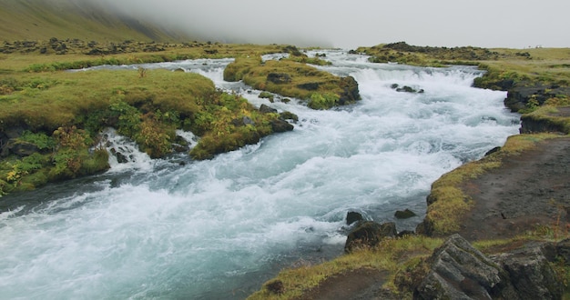 Água azul no rio da montanha com cascatas Foss cachoeira na Islândia