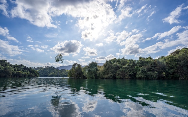 Água clara bonita em Cheow Lan Lake com luz da manhã, reflexão do céu azul