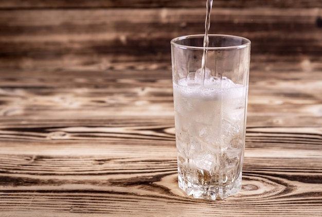 Água com gás fresca é colocada em um copo com gelo