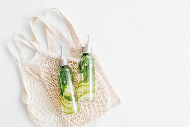 Água com infusão de limão e menta, coquetel, bebida detox, limonada em garrafas reutilizáveis com sacos ecológicos. Eco amigável. Estilo de vida sustentável.