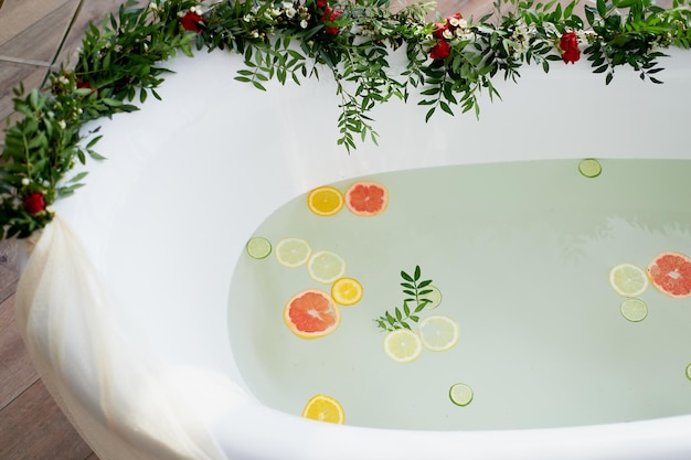 Água com leite no banho que nadam citrinos lima limão e toranjaCuidados com a pele e relaxamento Banho cheio de água e decorado com flores