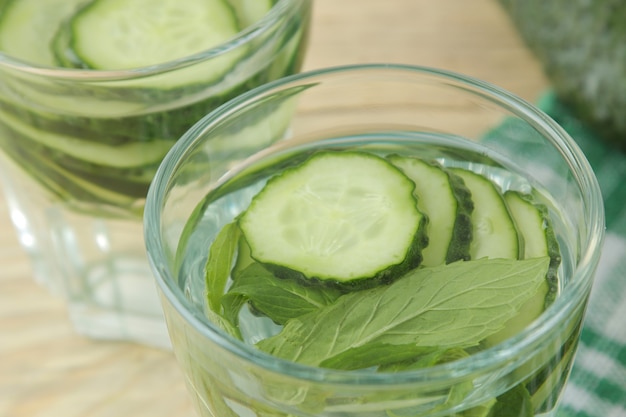 Água com pepino. Água de dieta refrescante com pepino e hortelã em um copo de vidro sobre uma mesa de madeira. conceito de bebida de desintoxicação.