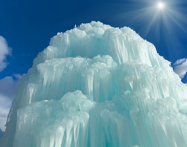 Água congelada na fonte (cachoeira de gelo) no fundo do céu ensolarado.