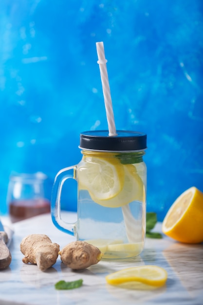 Água de gengibre em frasco de vidro com limão e mel na orientação vertical azul