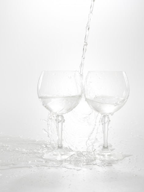 Água derramando da garrafa no copo, isolado no branco