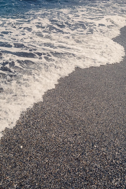 Água do mar de uma onda com espuma na praia