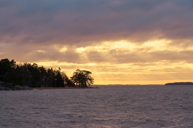 Água do mar tempestuosa em um pôr do sol com céu nublado