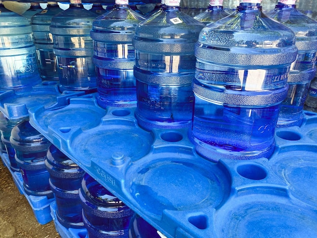 Água em garrafas grandes muitos recipientes com extração de cuidado ambiental de água purificada