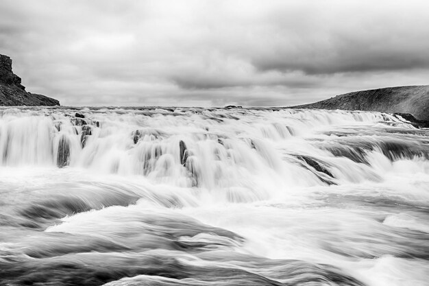 Água escorrer cachoeira na Islândia na paisagem montanhosa no céu nublado Férias viajando conceito de desejo de viajar