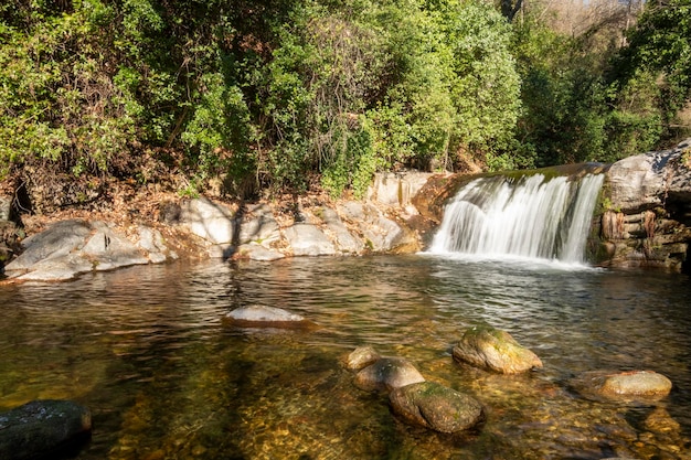 Água fluindo sobre rochas em cascata em uma floresta Efeito de água sedosa