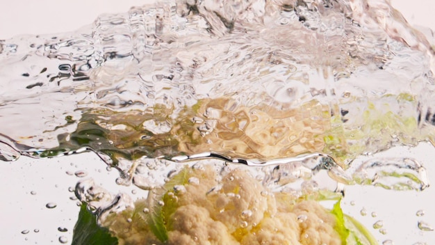 Água fresca caindo de couve-flor em closeup Vegetal de jardim orgânico salpicos