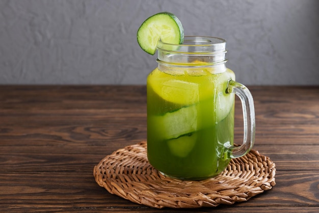 Água fresca de pepino com manjericão e limão em uma caneca de vidro na mesa de madeira