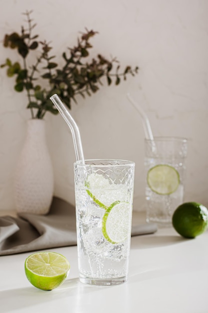 Água mineral com gás com gelo e limão em copos para refrescar na visão vertical de verão