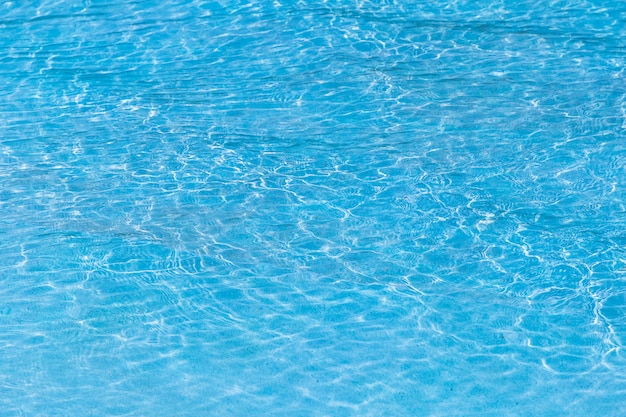 Água rasgada azul na piscina com reflexões ensolaradas.