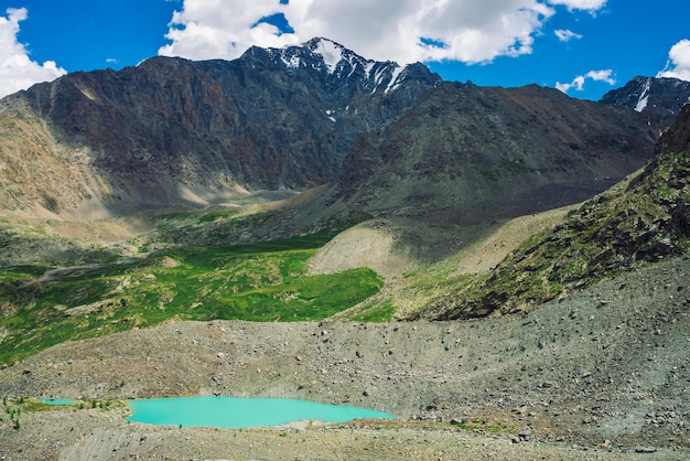 Água turquesa do lago de montanha perto da enorme montanha rochosa