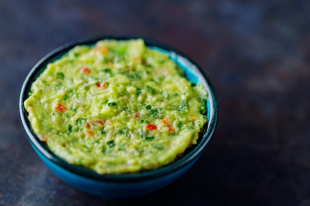 Guacamole auf dunklem Hintergrund. Traditionelle mexikanische Dip-Sauce Guacamole in einer Schüssel. Traditionelles mexikanisches Essen. Nahaufnahme