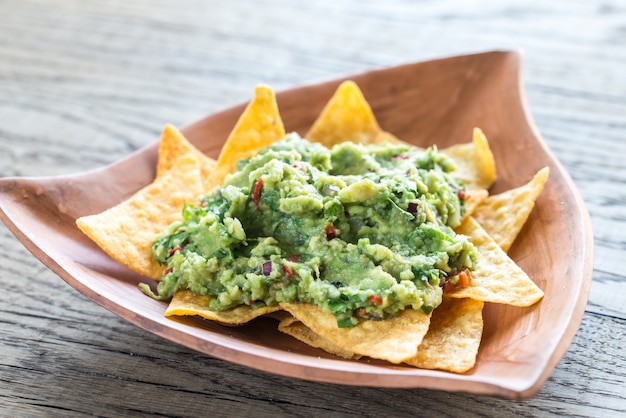 Guacamole com tortilla chips no fundo de madeira