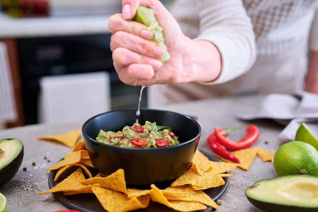 Guacamole-Dip mit Tortilla-Chips oder Nachos auf schwarzem Servierbrett