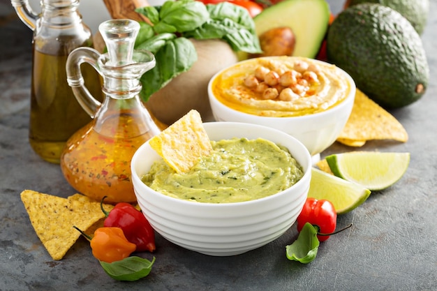 Guacamole e hummus em tigelas brancas