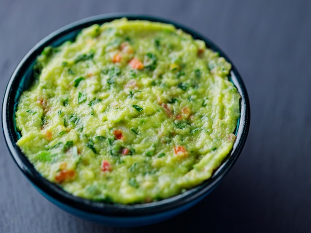 Guacamole em um fundo escuro. Molho de molho mexicano tradicional guacamole em uma tigela. Comida tradicional mexicana. Fechar-se