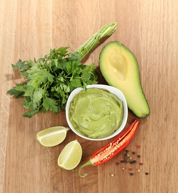 Foto guacamole fresco en un tazón sobre mesa de madera