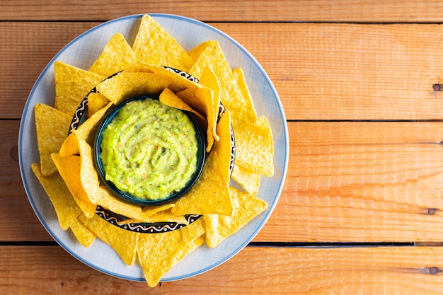 Guacamole mit Tortilla-Chips auf Holzbrettern. Nachos-Chips und mexikanische Guacamole-Sauce auf einem Teller. Platz kopieren. Ansicht von oben