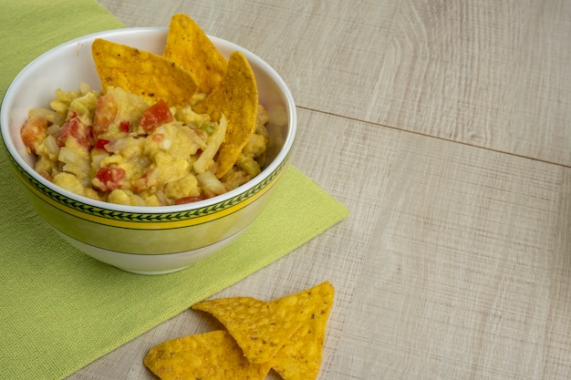 Guacamole mit Tortillas auf Holztisch.