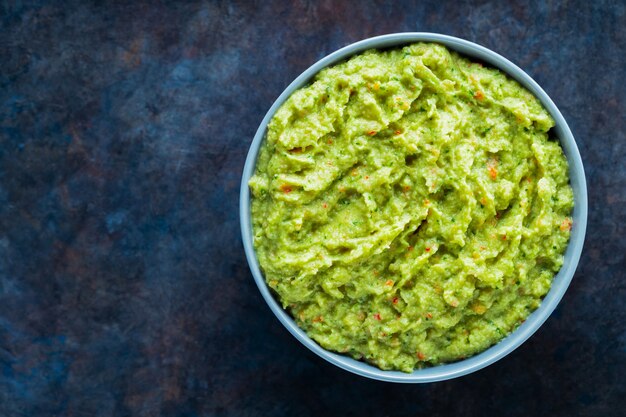 Guacamole en un recipiente gris sobre un fondo oscuro