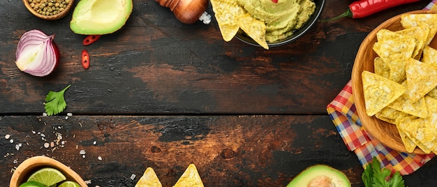 Foto guacamole. salsa tradicional mexicana latinoamericana en un tazón negro con aguacate e ingredientes y nachos de maíz. crema de aguacate. vista superior. copyspace