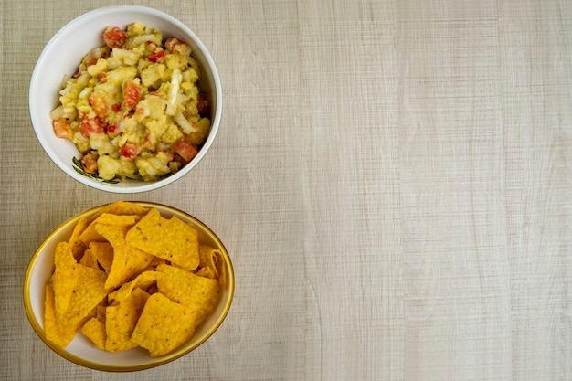 Guacamole con tortillas en mesa de madera.