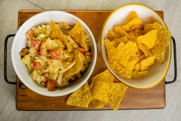 Guacamole con tortillas en mesa de madera.