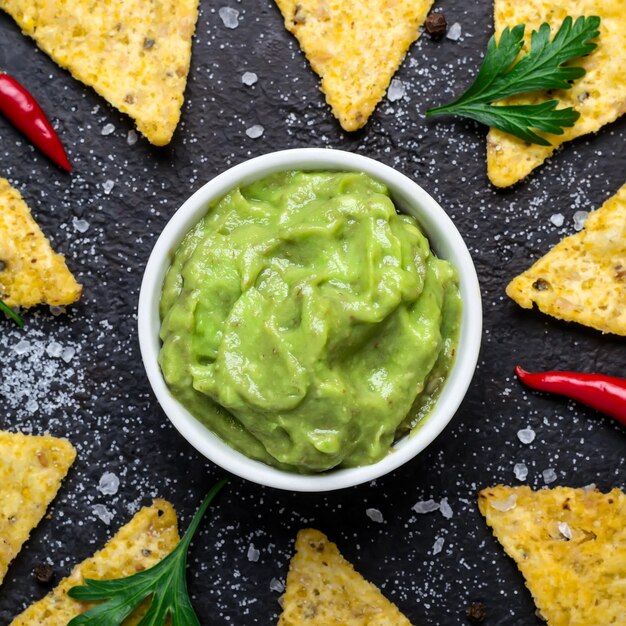 Foto guacamole tradicional latinoamericano con nachos con papas fritas de maíz en formato de bandera de fondo amarillo