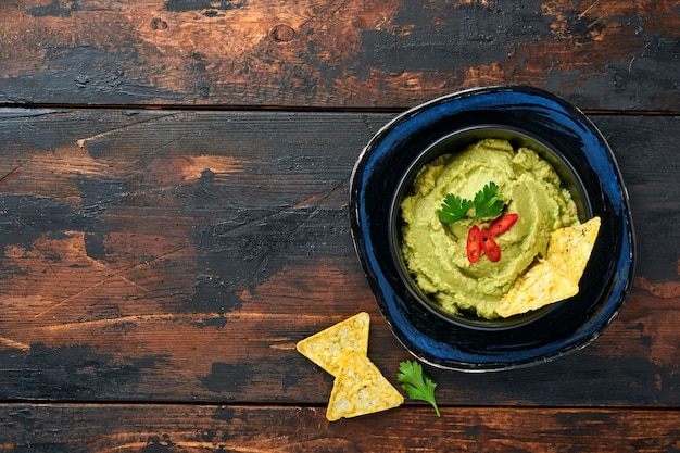 Guacamole. Traditionelle lateinamerikanische mexikanische Dip-Sauce in einer schwarzen Schüssel mit Avocado und Zutaten