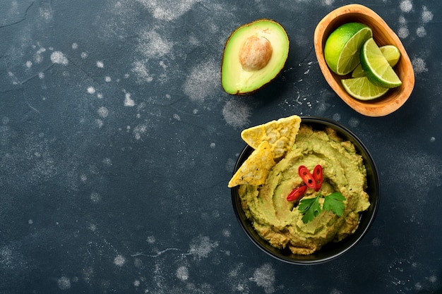 Foto guacamole. traditionelle lateinamerikanische mexikanische dip-sauce in einer schwarzen schüssel mit avocado und zutaten