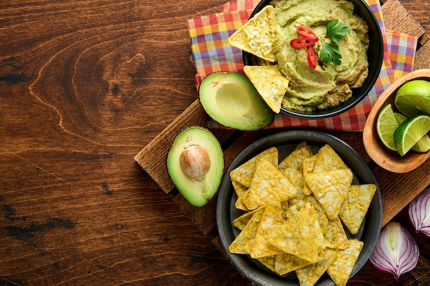 Guacamole. Traditionelle lateinamerikanische mexikanische Dip-Sauce in einer schwarzen Schüssel mit Avocado und Zutaten