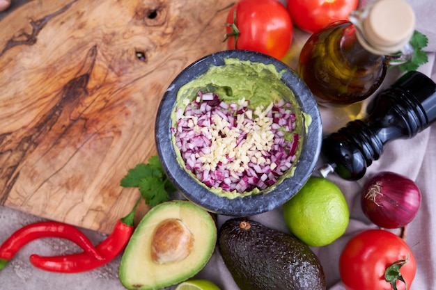 Guacamole zerkleinerte Avocado in Marmormörser und Zutaten zubereiten