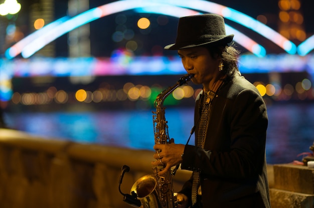 Foto guangzhou, china - 15 de março de 2016: homem tocando saxofone na rua à noite