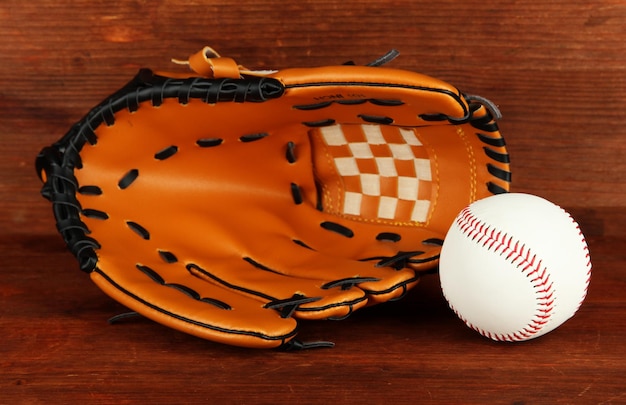 Guante de béisbol y pelota sobre fondo de madera