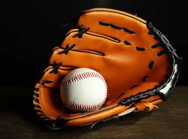 Foto guante de béisbol y pelota sobre fondo oscuro