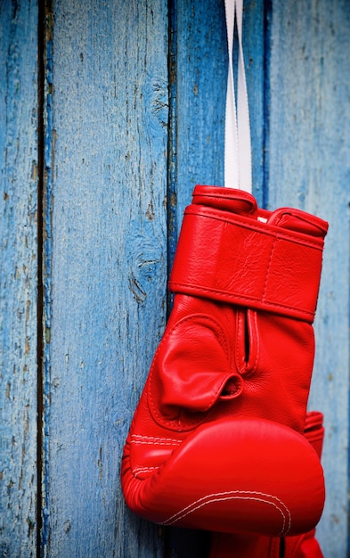 Guante de kickboxing rojo colgado en una superficie de madera azul