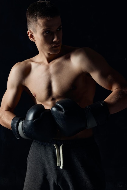 Guantes de boxeo de atleta masculino en entrenamiento de fondo negro