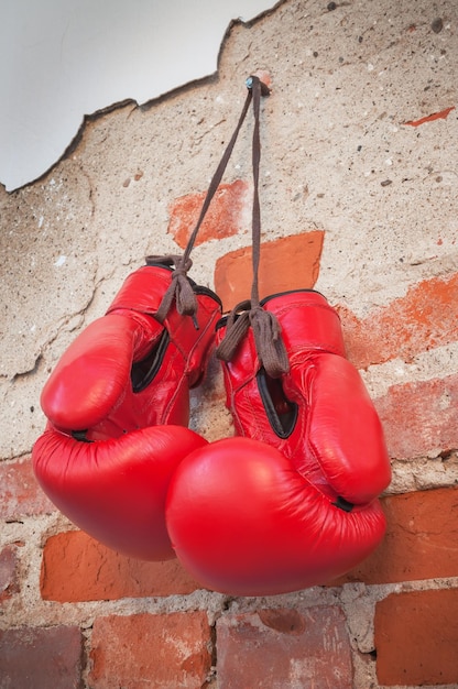 Guantes de boxeo colgando de un clavo en la pared de ladrillo