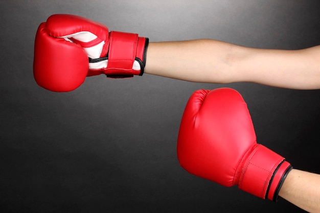 Guantes de boxeo rojos en las manos sobre fondo gris